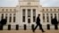 FILE - A man walks past the Federal Reserve building in Washington, D.C., Dec. 16, 2015.