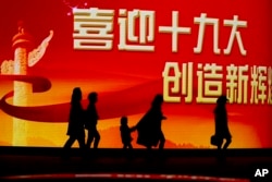 北京居民走过迎接中共十九大召开的大型电子屏幕。（2017年10月15日）