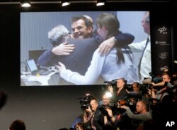 FILE - Scientists celebrating in the main control room appear on a video screen at the European Space Agency after the first unmanned spacecraft Philae landed on a comet called 67P/Churyumov-Gerasimenko, in Darmstadt, Germany, Nov. 12, 2014.