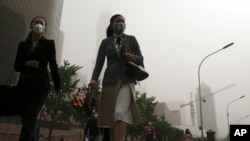 Para pekerja mengenakan masker berjalan di jalanan di Beijing yang dilanda polusi udara dan badai pasir, 4 Mei 2017. 