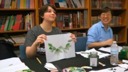 An undergraduate student, left, shows her watercolor painting at a traditional Chinese painting class at the Confucius Institute at George Mason University in Fairfax, Va., on May 2, 2018.