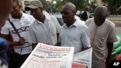 People read newspapers with election headlines on the street in Abuja, Nigeria Monday, March 30, 2015. Nigerians are waiting for results of the tightest and most bitterly contested presidential election in the nation's turbulent history. (AP Photo/Sunday Alamba)