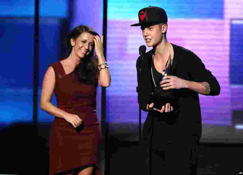 Justin Bieber menerima penghargaan Artis Tahun Ini didampingi oleh ibunyda Pattie Malette pada ajang American Music Awards (18/11) di Los Angeles.