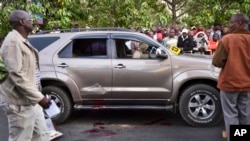 FILE - Onlookers gather at the scene where Kenyan lawmaker George Muchai, his two bodyguards and driver were killed in Nairobi, Kenya, Feb. 7, 2015.