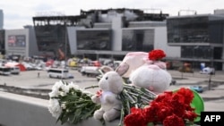 Flowers and toys left at the side of a road near the burnt-out Crocus City Hall concert venue in Krasnogorsk, outside Moscow, on March 26, 2024. (Natalia Kolesnikova/AFP)