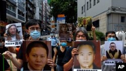 Pro-democracy demonstrators hold up portraits of jailed Chinese civil rights activists, lawyers and legal activists as they march to the Chinese liaison office in Hong Kong, June 25, 2020. 