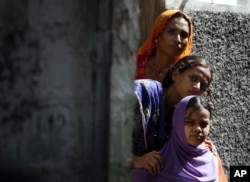 FILE - A woman and two girls peer out from a doorway in a Hindu neighborhood in Lyari, in Karachi, Pakistan, May 5, 2009.