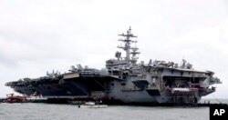 FILE- The U.S. aircraft carrier USS Ronald Reagan is seen anchored off Manila Bay, Philippines, Aug. 7, 2019, for a port call after sailing through the disputed South China Sea amid new territorial flare-ups involving China and rival claimant states.