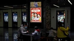 Para pengunjung, yang menggunakan masker untuk mencegah penyebaran virus, menunggu giliran masuk ke bioaskop di Poly Cinema, di Beijing, China, 25 Februari 2021. (Foto: Andy Wong/AP)