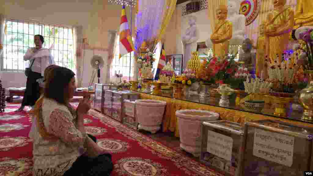 ស្ត្រី​ពីរ​នាក់​បួងសួង​នៅ​មុខ​រូបសំណាក​ព្រះពុទ្ធ នៅ​ក្នុង​វត្ត​សំពៅមាស ក្នុង​រាជធានី​ភ្នំពេញ នៅ​ថ្ងៃ​កាន់​បិណ្ឌ​ទី៥ (ថ្ងៃទី២១ ខែកញ្ញា ឆ្នាំ២០១៦)។ (ប៊ុន ប៉េងហ៊ុយ/VOA)