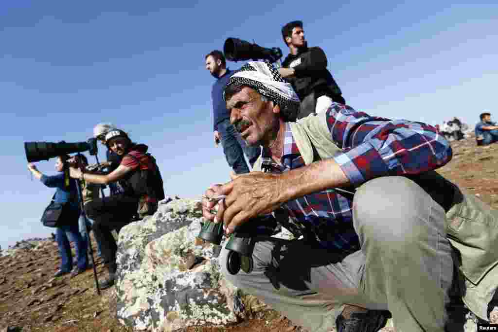 Turkish Kurds watch the Syrian town of Kobani from a hill near the Syria-Turkey border, Oct. 24, 2014. 