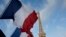 French flags fly as the closed Eiffel Tower is seen in the background on the first of three days of national mourning in Paris, Nov. 15, 2015. 