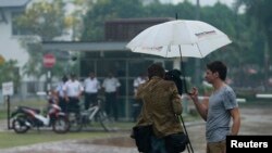 A journalist from France films the entrance of the compound where the home of pilot Zaharie Ahmad Shah, the captain of Malaysia Airlines flight MH370, is located in Shah Alam, near Kuala Lumpur March 16, 2014. Police began searching the home of Zaharie on