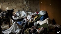 People suffering cholera symptoms rest on stretchers as they crowd the entrance of a public hospital in Limbe village near Cap-Haïtien, Haiti, 22 Nov 2010