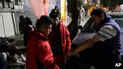 Migrant shelter director Jose Garcia, right, gives a few coins to two men from Guatemala on their way to cross into the United States in Tijuana, Mexico, Nov. 14, 2016.