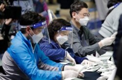 South Korean National Election Commission officials wearing masks and face shields, sort out ballots for counting at the parliamentary election at a ballot counting office in Seoul, April 15, 2020.