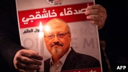 Seorang demonstran memegang poster bergambar jurnalis Saudi Jamal Khashoggi dan lilin yang menyala saat berkumpul di luar konsulat Arab Saudi di Istanbul, pada 25 Oktober 2018. (Foto: AFP/Yasin Akgul)