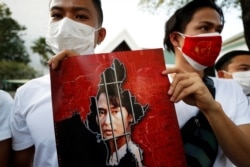 Myanmar citizens hold up a picture of leader Aung San Suu Kyi after the military seized power in a coup in Myanmar, outside United Nations venue in Bangkok, Thailand, Feb. 2, 2021.