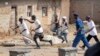 FILE - Members of the Imbonerakure pro-government youth militia chase after opposition protesters, unhindered by police, in the Kinama district of the capital Bujumbura, in Burundi, May 25, 2015. 