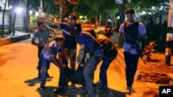 People help an unidentified injured person after a group of gunmen attacked a restaurant popular with foreigners in the Bangladeshi capital Dhaka.