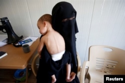 FILE - Chechen Laila Magomedovna Gazieva, the widow of an Islamic State militant, holds her son Obaida at Hammam Al-Alil camp south of Mosul, Iraq, Sept. 13, 2017.