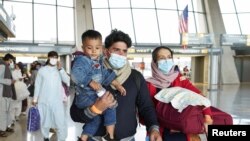 Afghan refugees walk to a bus taking them to a processing center upon arrival at Dulles International Airport in Dulles, Virginia, Aug. 26, 2021.