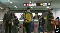 FILE - People wearing face masks to protect against the spread of the coronavirus go through gates of a metro in Taipei on Dec. 29, 2020. 