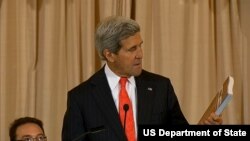 美国国务卿克里在发布会上手持《2014年世界人口走私状况报告》(2014年6月20日， 美国国务院视频截图)