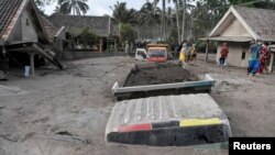 Sebuah truk dan rumah-rumah warga diselimuti abu vulkanik akibat letusan Gunung Semeru (5/12).
