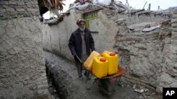 FILE - An Afghan man uses a wheelbarrow to move containers of water in Kabul, Feb. 12, 2018.