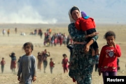 Displaced Yazidis, fleeing violence from forces loyal to the Islamic State group in Sinjar, Iraq, head toward the Syrian border Aug. 11, 2014.