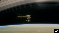 This image made available by NASA in April 2017 shows a still from the short film "Cassini's Grand Finale," with the spacecraft diving between Saturn and the planet's innermost ring. 