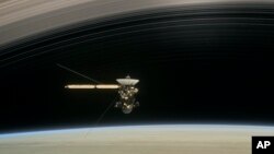 This image made available by NASA in April 2017 shows a still from the short film "Cassini's Grand Finale," with the spacecraft diving between Saturn and the planet's innermost ring. 