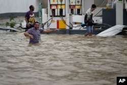 People walk next to a gas station flooded and damaged by the impact of Hurricane Maria, which hit the eastern region of the island, in Humacao, Puerto Rico, Sept. 20, 2017.