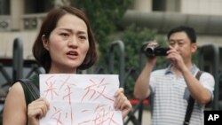 Li Wenzu, istri pengacara HAM China yang sedang dipenjara, Wang Quanzhang, memegang kertas bertuliskan permintaan pembebasan para pengacara, di Tianjin, China. (Foto: Dok)