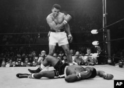 FILE - Heavyweight champion Muhammad Ali stands over fallen challenger Sonny Liston, shouting and gesturing shortly after dropping Liston with a short hard right to the jaw, in Lewiston, Maine, May 25, 1965.