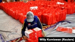 Seseorang mengemas sembako untuk dibagikan secara gratis di tengah penyebaran COVID-19 di Jakarta, 17 April 2020, sebagai ilustrasi. Gerakan solidaritas ekonomi bermunculan di masa pandemi. di antaranya Teman Bantu Teman dan BagiRata. (Foto: REUTERS/Willy Kurniawan)