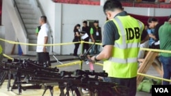 A member of the Independent Decommissioning Body inspects and tags weapons turned over by Moro Islamic Liberation Fighters at a ceremonial laying down of arms in Sultan Kudarat, Maguindanao Province, the Philippines, June 16, 2015. (VOA/Simone Orendain)