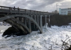 In this Jan. 11, 2020 photo heavy surf surrounds the legs of a bridge as an extreme high tide rolls into the harbor in Depoe Bay, Oregon, USA. (AP Photo/Gillian Flaccus)