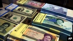 FILE - Iranian and U.S. banknotes are on display at a currency exchange shop in downtown Tehran, Iran, on April 4, 2015.