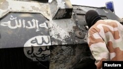 A Chadian soldier peers into a burnt armored vehicle, which the Chadian military say belonged to insurgent group Boko Haram, after the Chadians destroyed it during battle in Gambaru, Feb. 26, 2015.