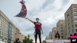 Protester waves U.S. flag with "Black Lives Matter" spray painted on it, Washington, DC, June 19, 2020.