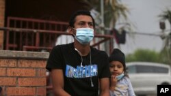 In this March 28, 2021, file photo, Carlos Enrique Linga and his daughter Betty Noemi talk to a reporter at Our Lady of Guadalupe Catholic Church in Mission, Texas, on Palm Sunday. 