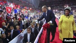 Turkey's PM and leader of ruling Justice and Development Party (AKP) Tayyip Erdogan, accompanied by his wife Emine Erdogan (R), throws carnations to supporters during his party congress in Ankara, September 30, 2012.