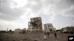 Người dân đứng gần một tòa nhà bị không kích ở Sana'a, Yemen, hôm 6/7/2015. 