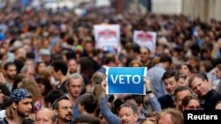 Seorang pengunjuk rasa mengangkat poster yang berbunyi “Veto” selama rapat akbar, menentang undang-undang baru yang disetujui oleh parlemen Hungaria yang dapat memaksa Central European University yang didirikan oleh Soros keluar dari Hungraria, yang diselenggarakan di Budapest, tanggal 4 April 2017 (foto: REUTERS/Laszlo Balogh)