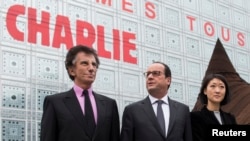 Presiden Perancis Francois Hollande (tengah) didampingi Menteri Kebudayaan Fleur Pellerin (kanan) dan Presiden Arab Institut 'Institut du Monde Arabe', Jack Lang (kiri) melewati dinding bertuliskan "We are Charlie" di kampus institusi pendidikan tersebut di Paris (15/1).
