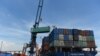 FILE - Containers are transferred from a truck to a cargo ship at the international cargo terminal of a port in Hai Phong, Vietnam, Aug. 12, 2019.