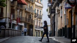 A waitress carries a tray across the road to a terrace bar in Seville, Spain, Monday, May 11, 2020. (AP Photo/Miguel Morenatti)