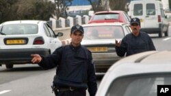Des policiers contrôlent des véhicules à une barrière, à Alger. 18 mars 2005.